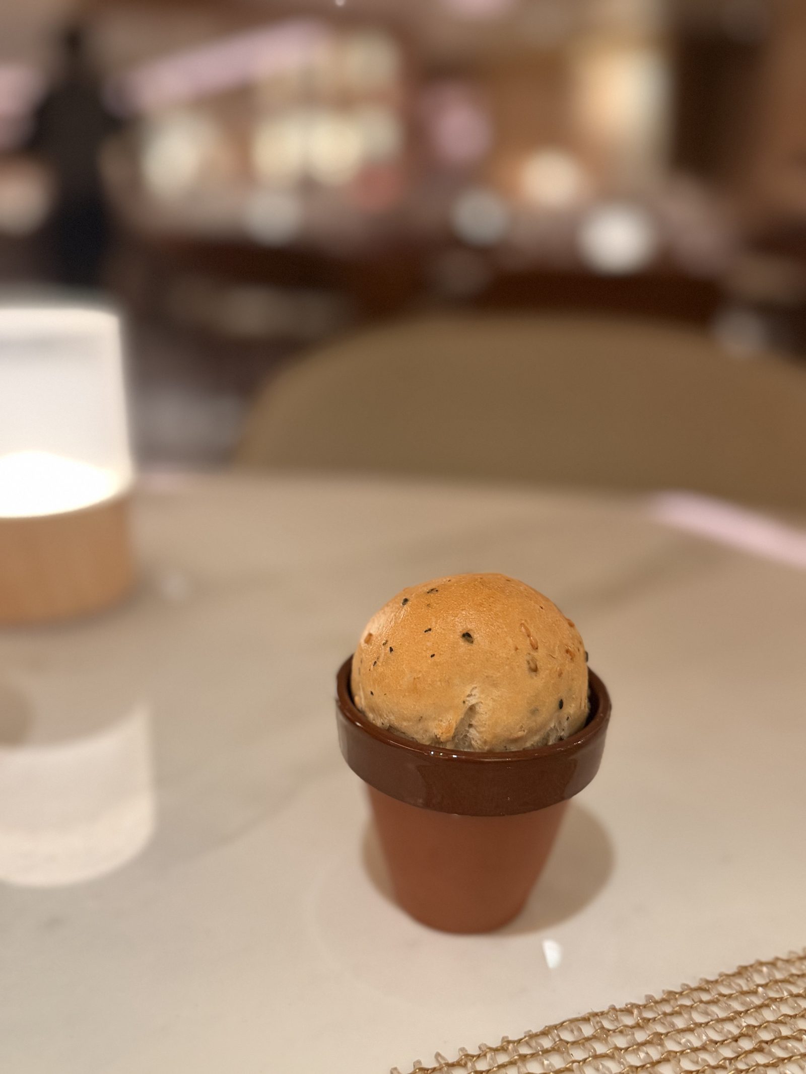 小さなテラコッタの器に入った丸パン。表面にハーブの粒が見えます。