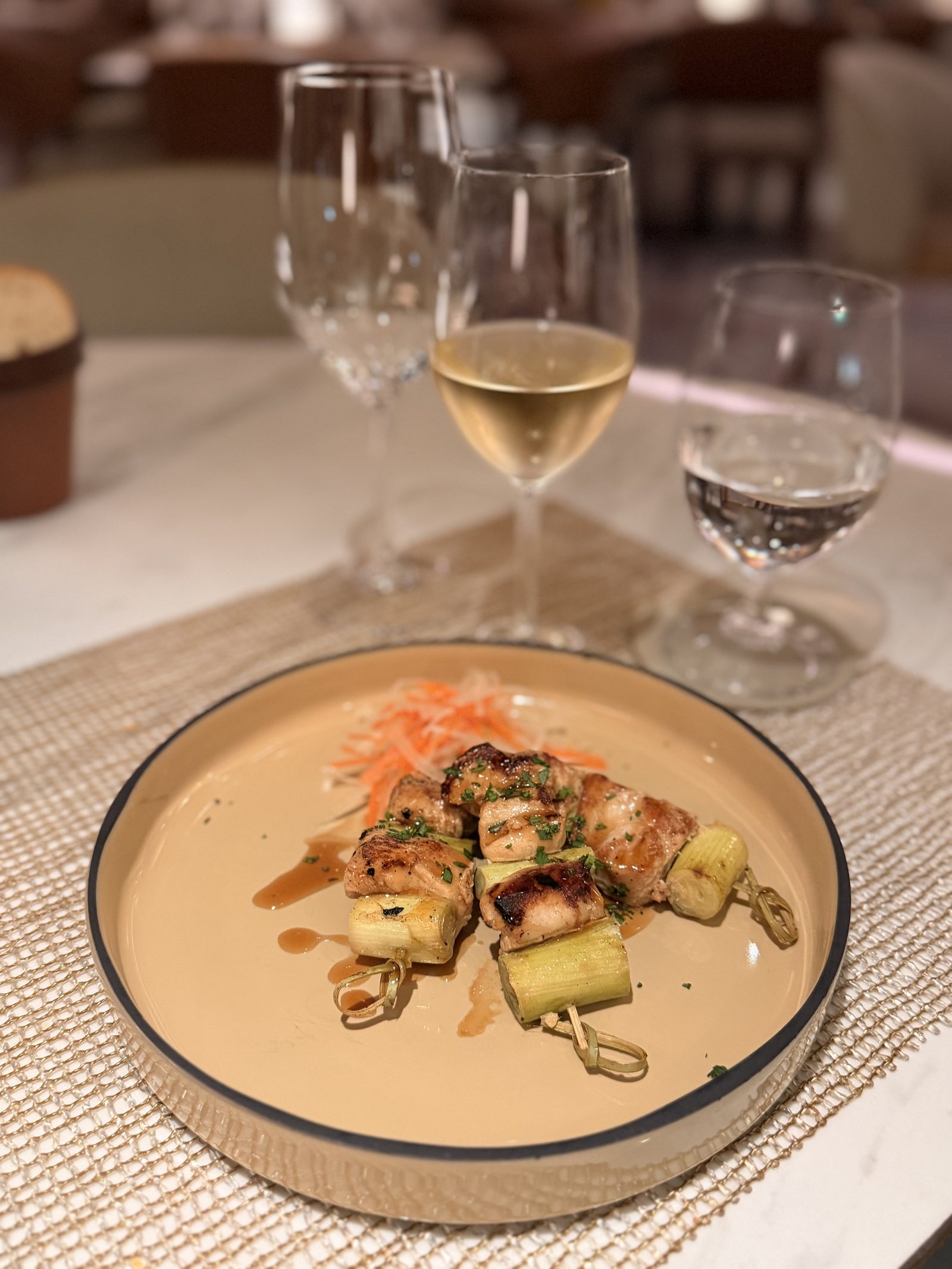 前菜「ねぎま焼き鳥」。鶏肉とねぎの串焼きにタレの照り、千切りの大根とにんじんを添えて。