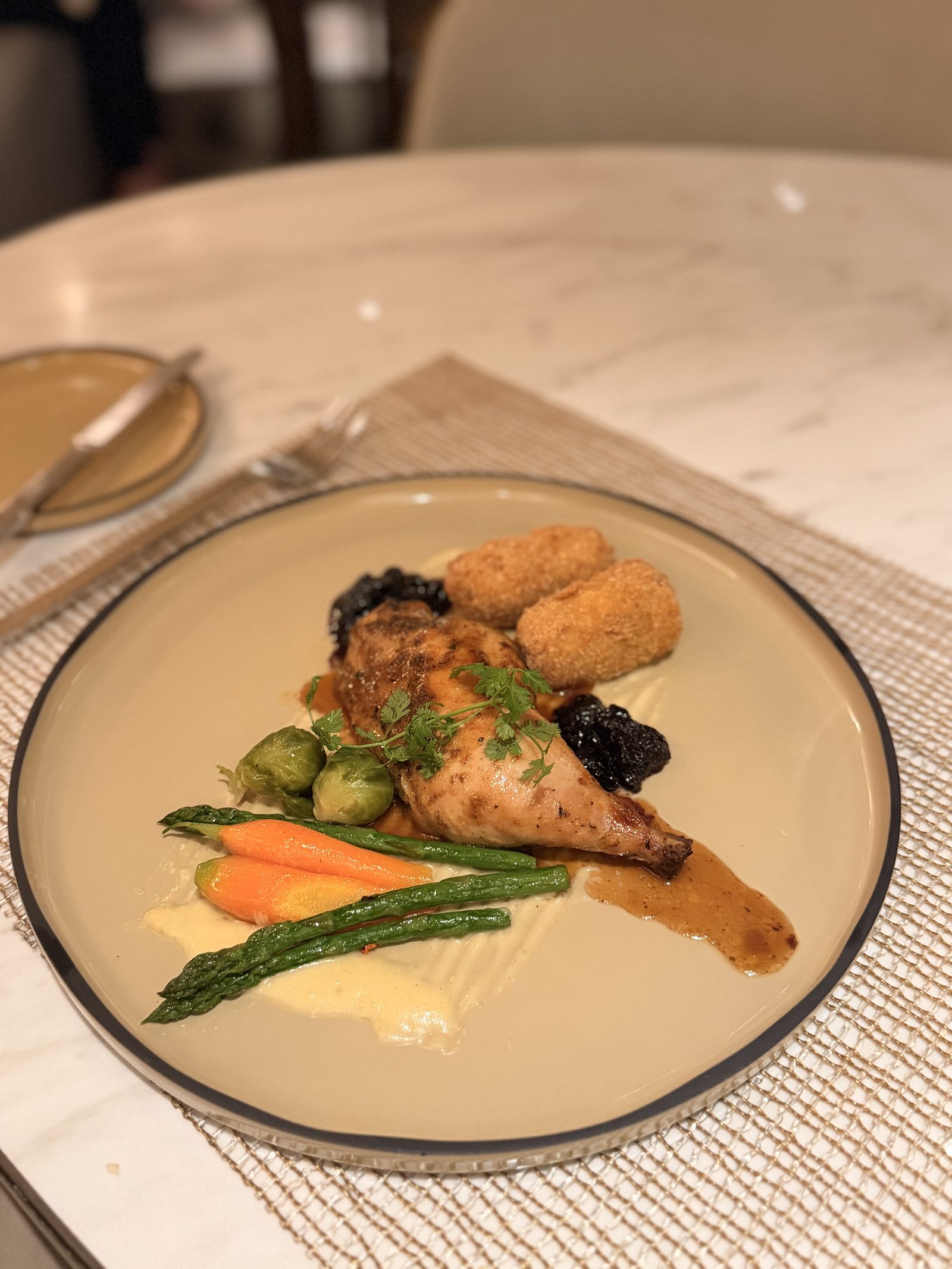メイン「ローストチキン」。鶏もも肉のローストに、リーキとじゃがいものコロッケ、アスパラガス、ミニにんじんと芽キャベツ。