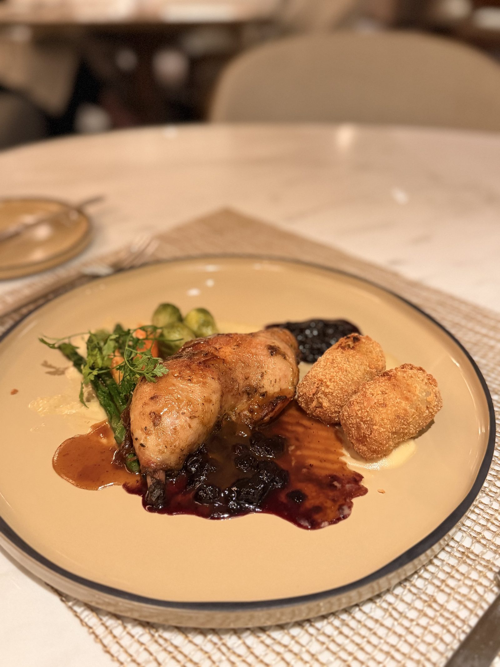 ローストチキンのアップ。皿には濃いベリーのソース。