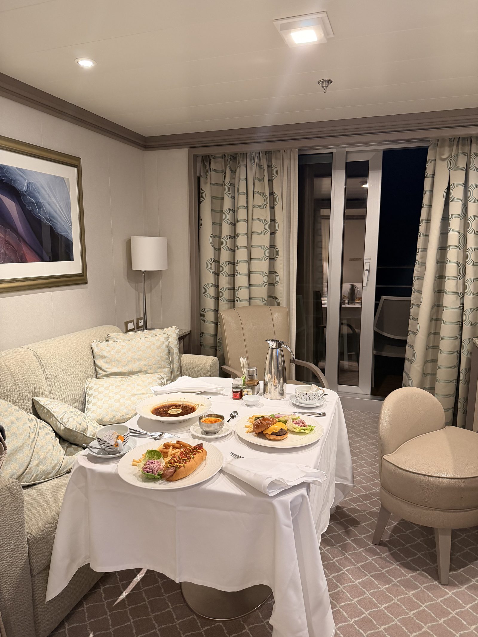 深夜のルームサービス。スイートのリビングの円卓に白いクロスを敷き、夜食がきちんと並びました。バルコニーの外は夜。