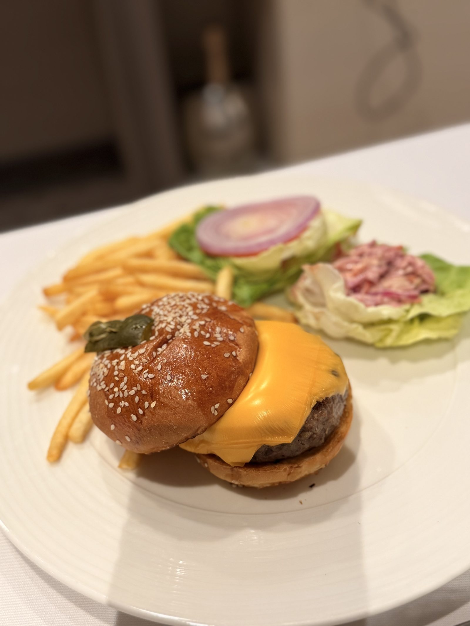 チーズバーガー。ごまのブリオッシュバンズと溶けたチェダー、フライ、レタスとコールスローを添えて。