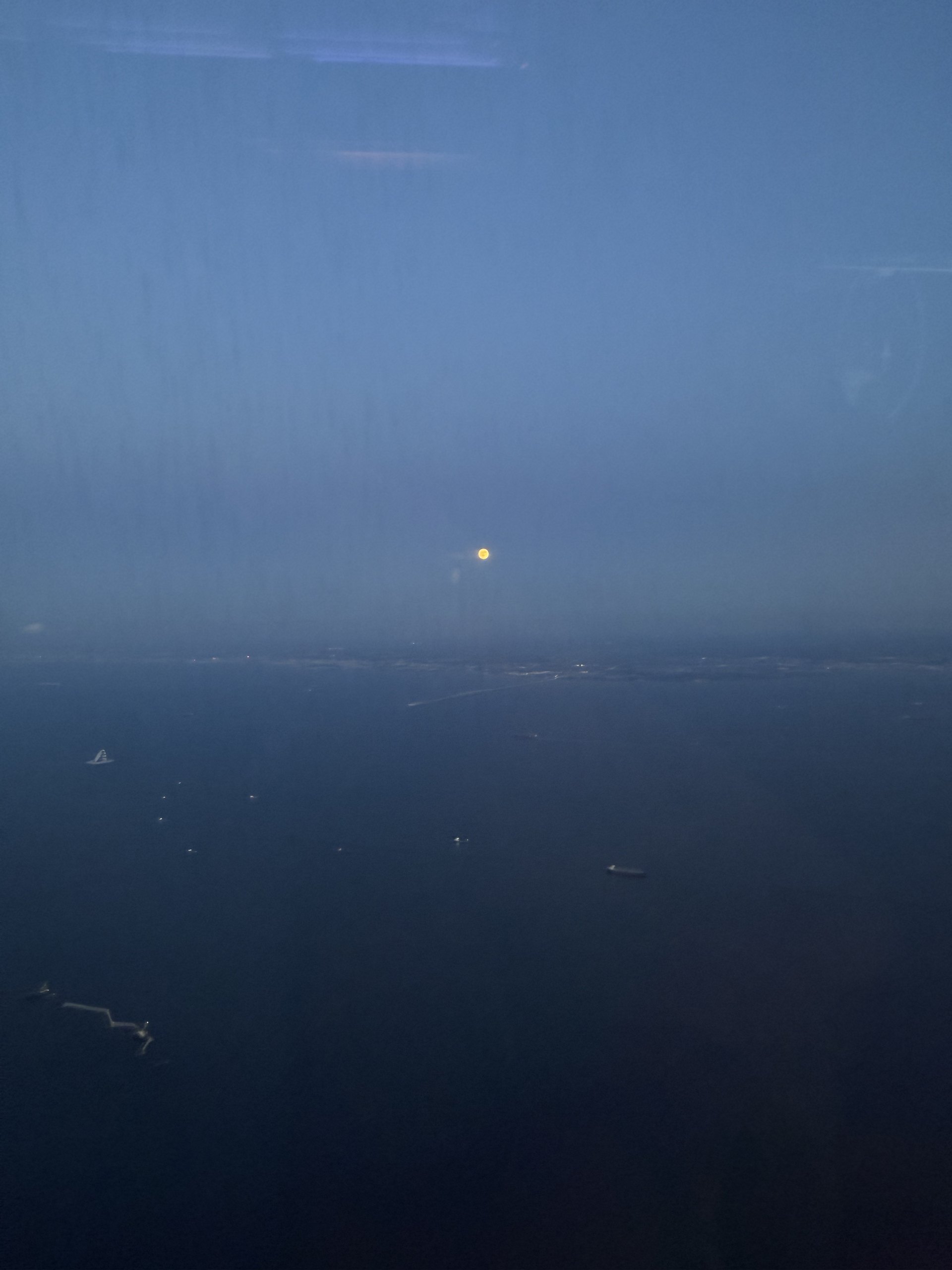 夜の海面。遠くに小さな灯りがひとつ。