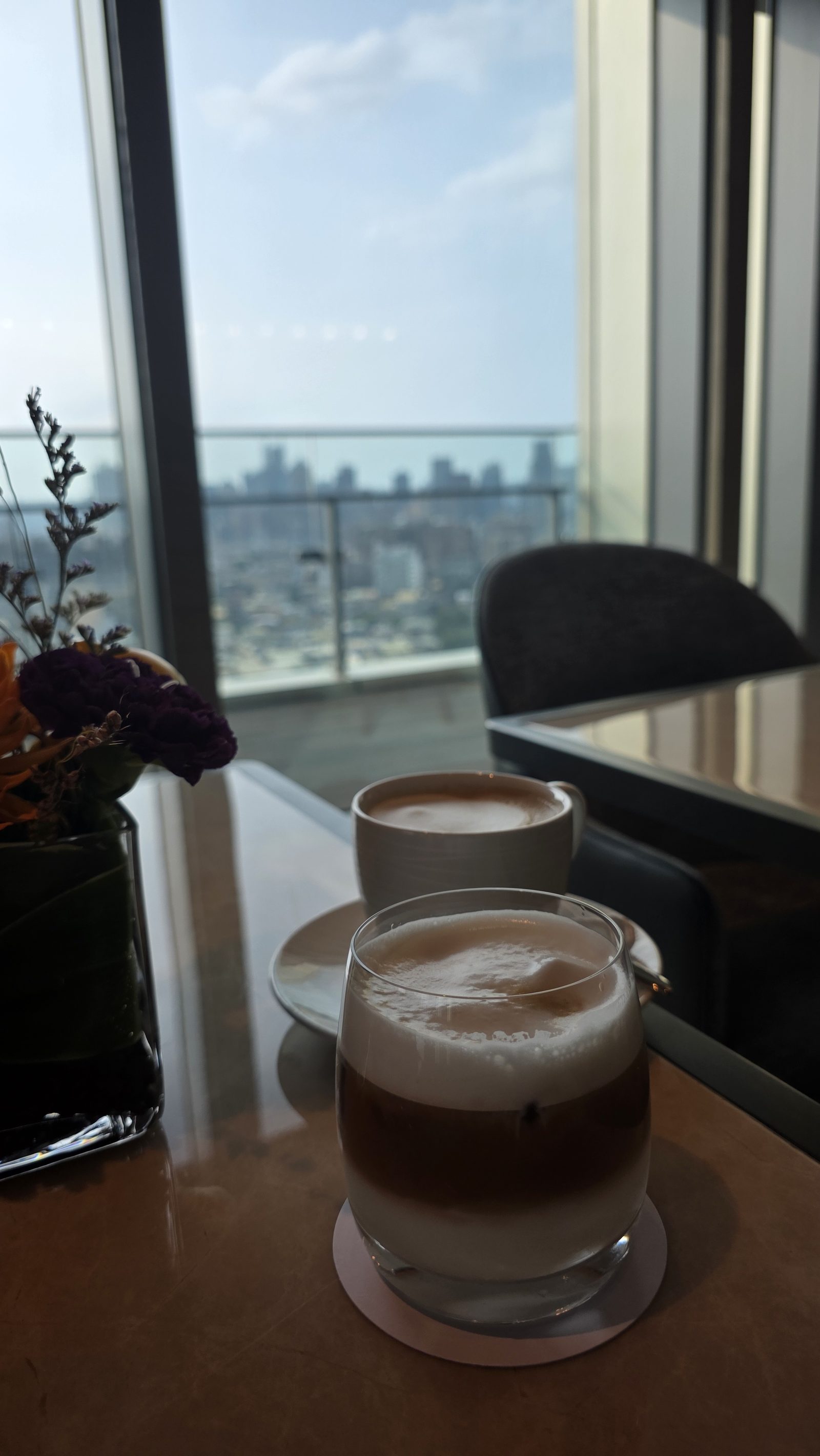 By the window: a hot latte and an iced latte, the afternoon city outside