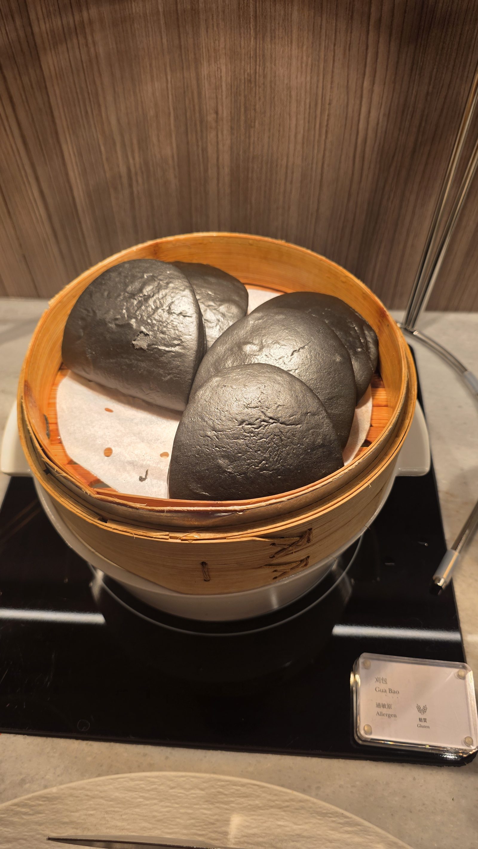 Black gua bao skins in a bamboo steamer