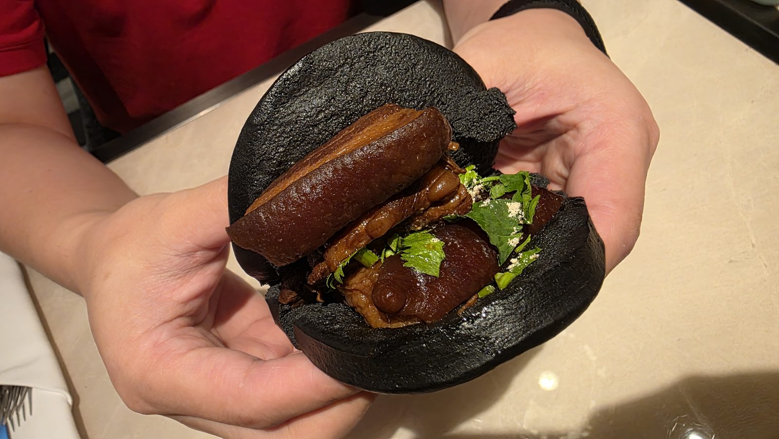 A gua bao assembled: black skin, filling and lettuce