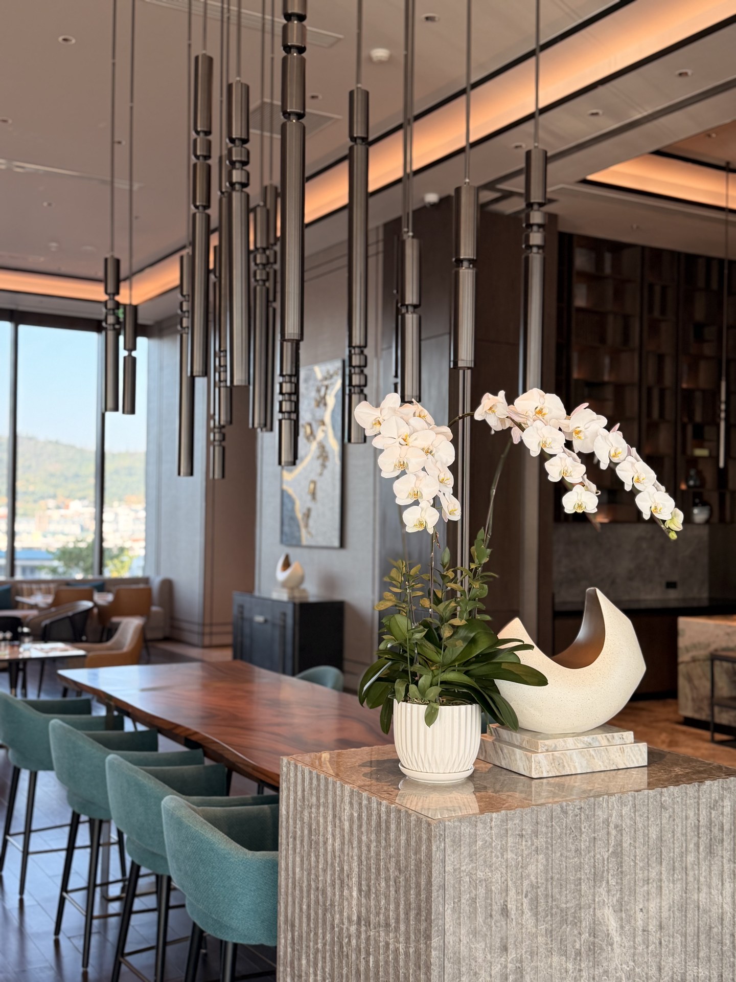 The lounge's communal table, turquoise chairs and white phalaenopsis orchids.
