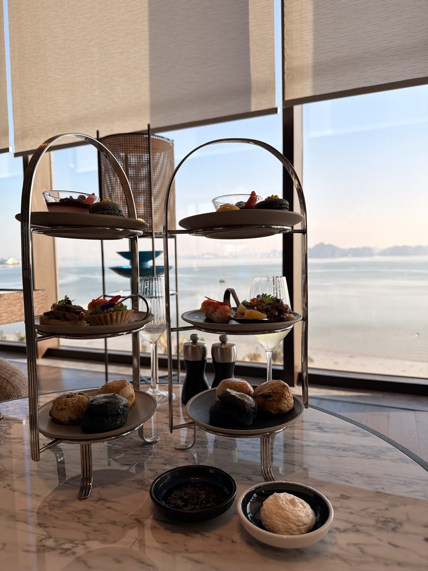 Two three-tier afternoon-tea stands, karst islets beyond the glass.
