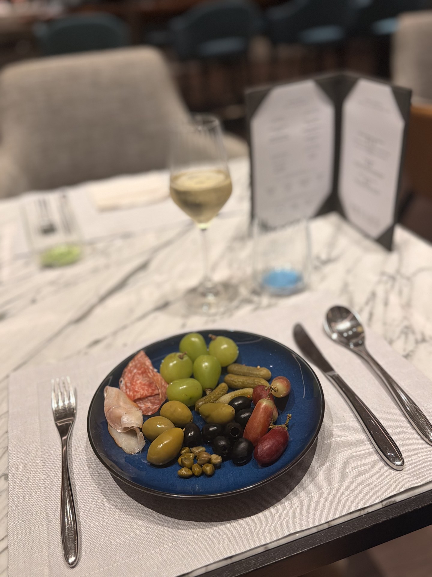 An olive and cold-cut plate at the table.