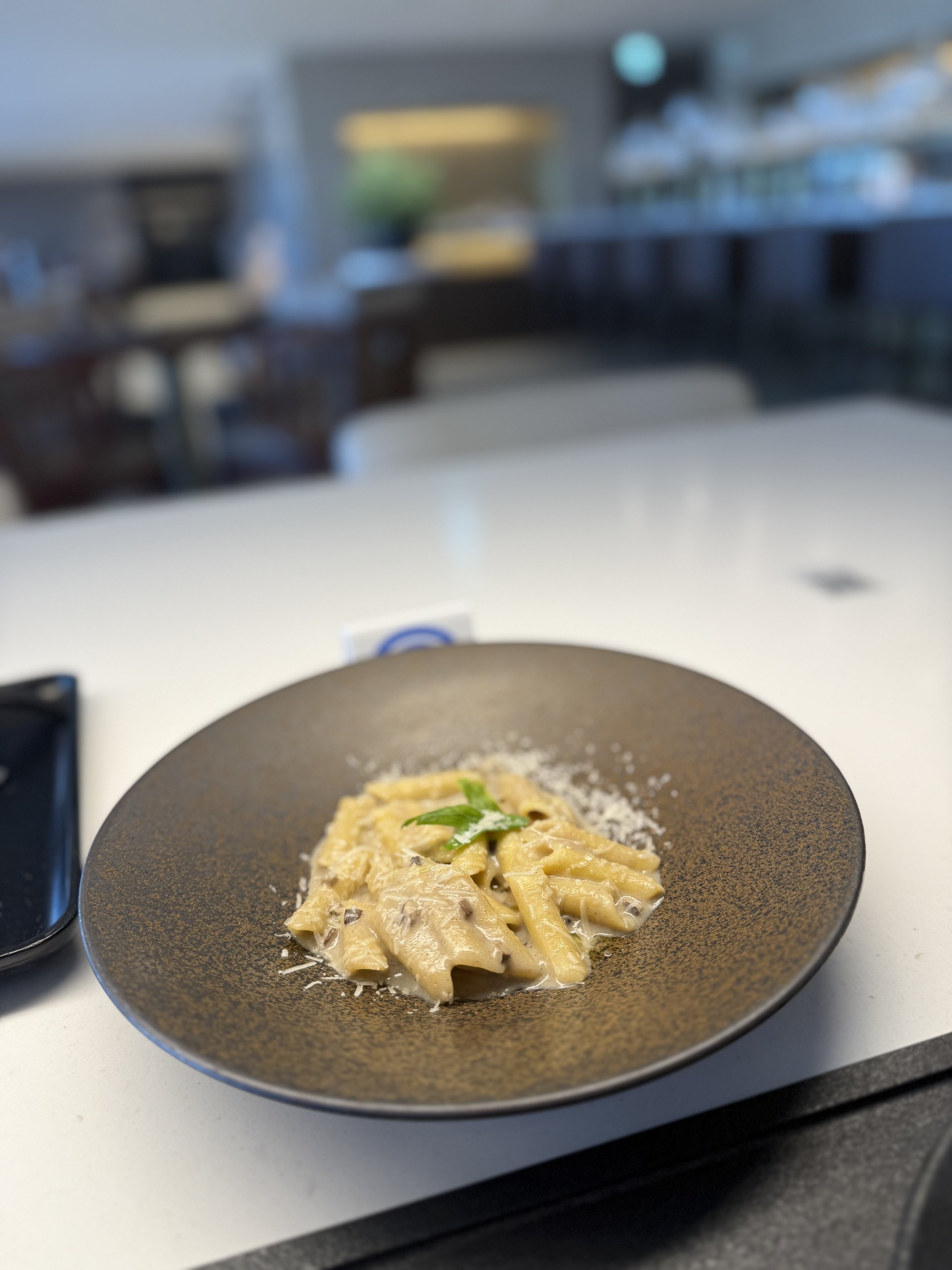 Penne in a cream sauce, finished with grated cheese and a basil leaf.