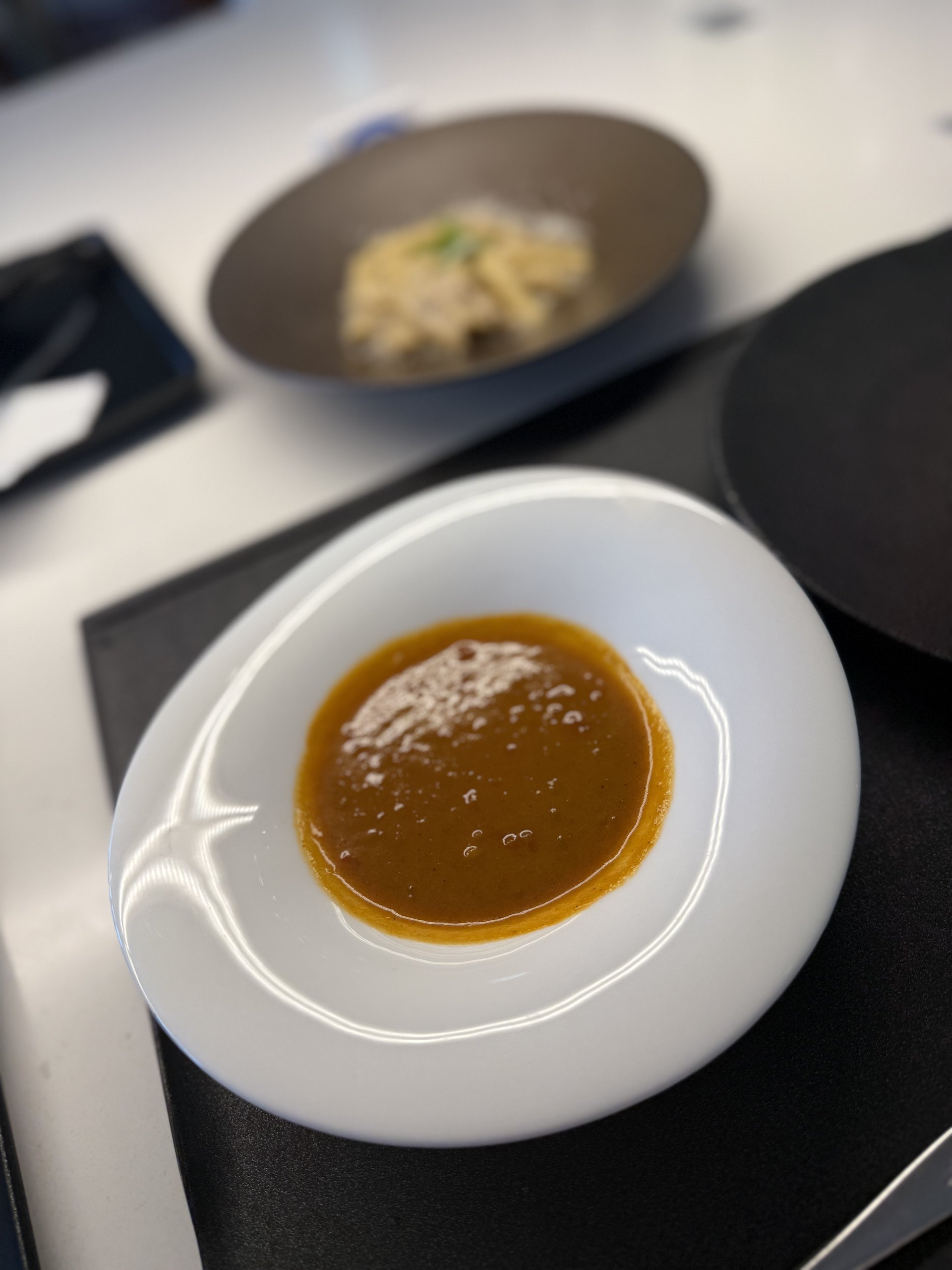 Curry: a dark brown sauce in a white bowl, still glossy with oil.
