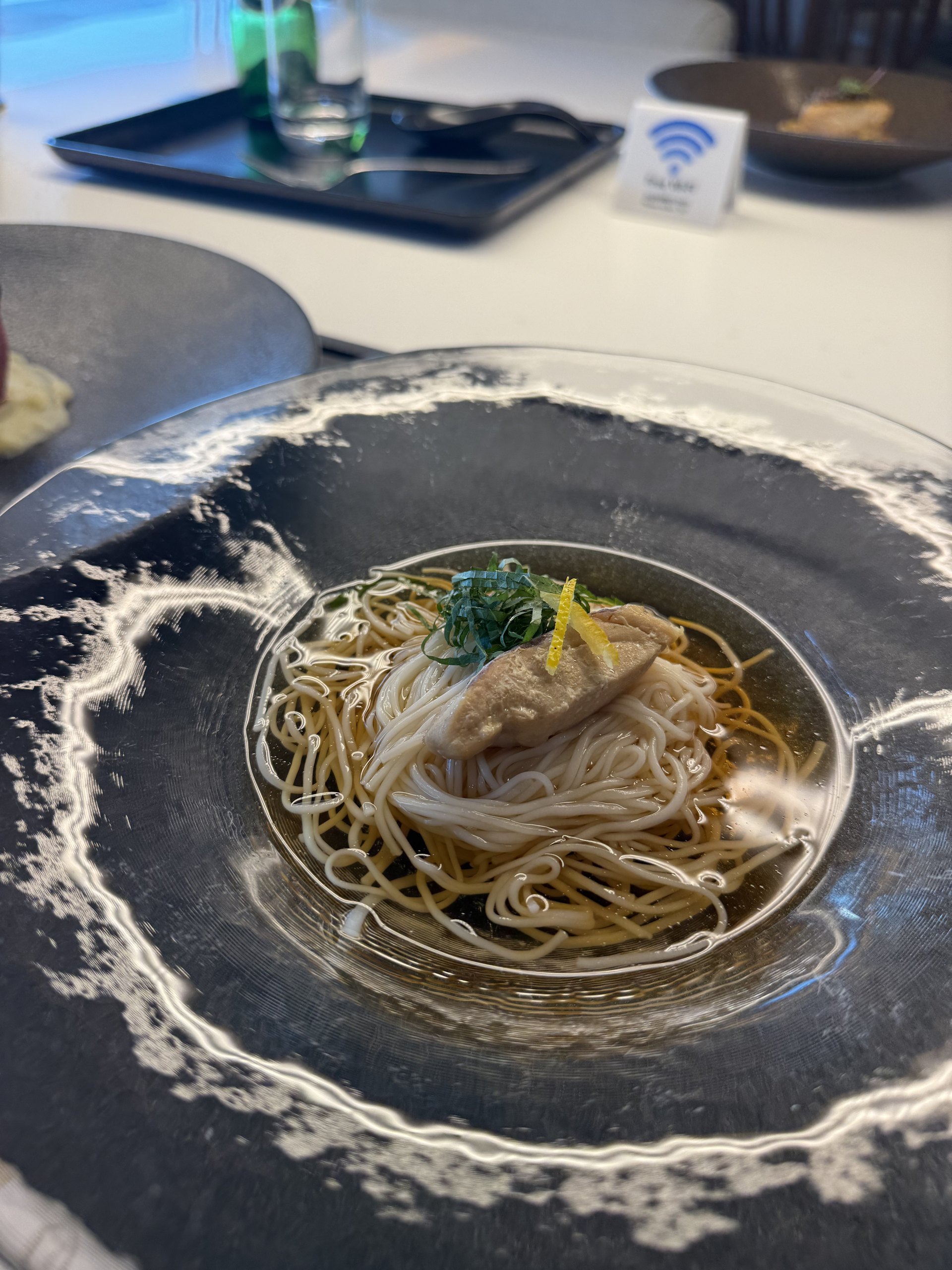 The chilled noodles up close: a neat bundle in clear broth, topped with fish, shiso and lemon zest.