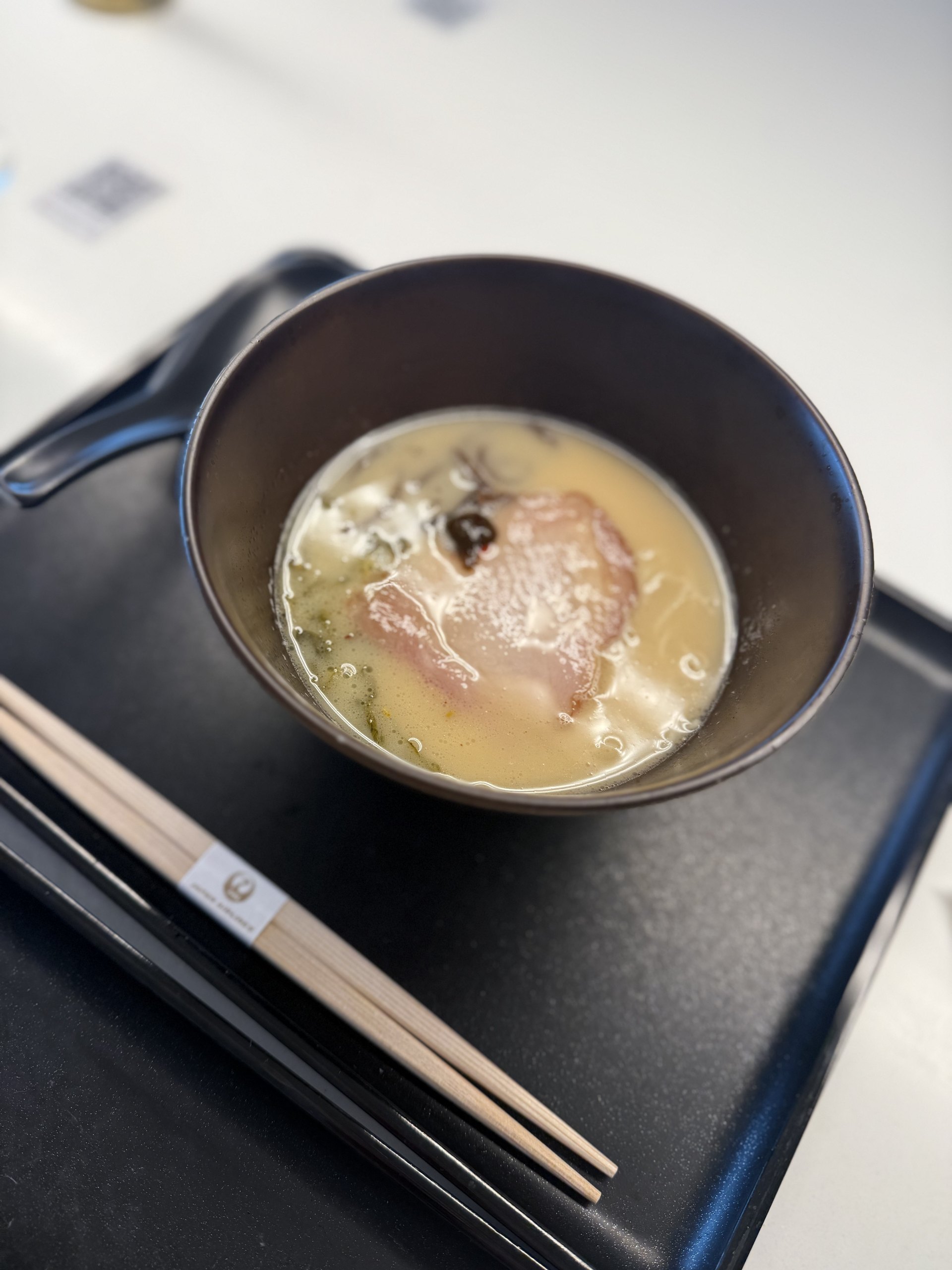 One last bowl of ramen: milky broth, chashu and wood-ear mushroom, with JAL's mark on the chopstick sleeve.